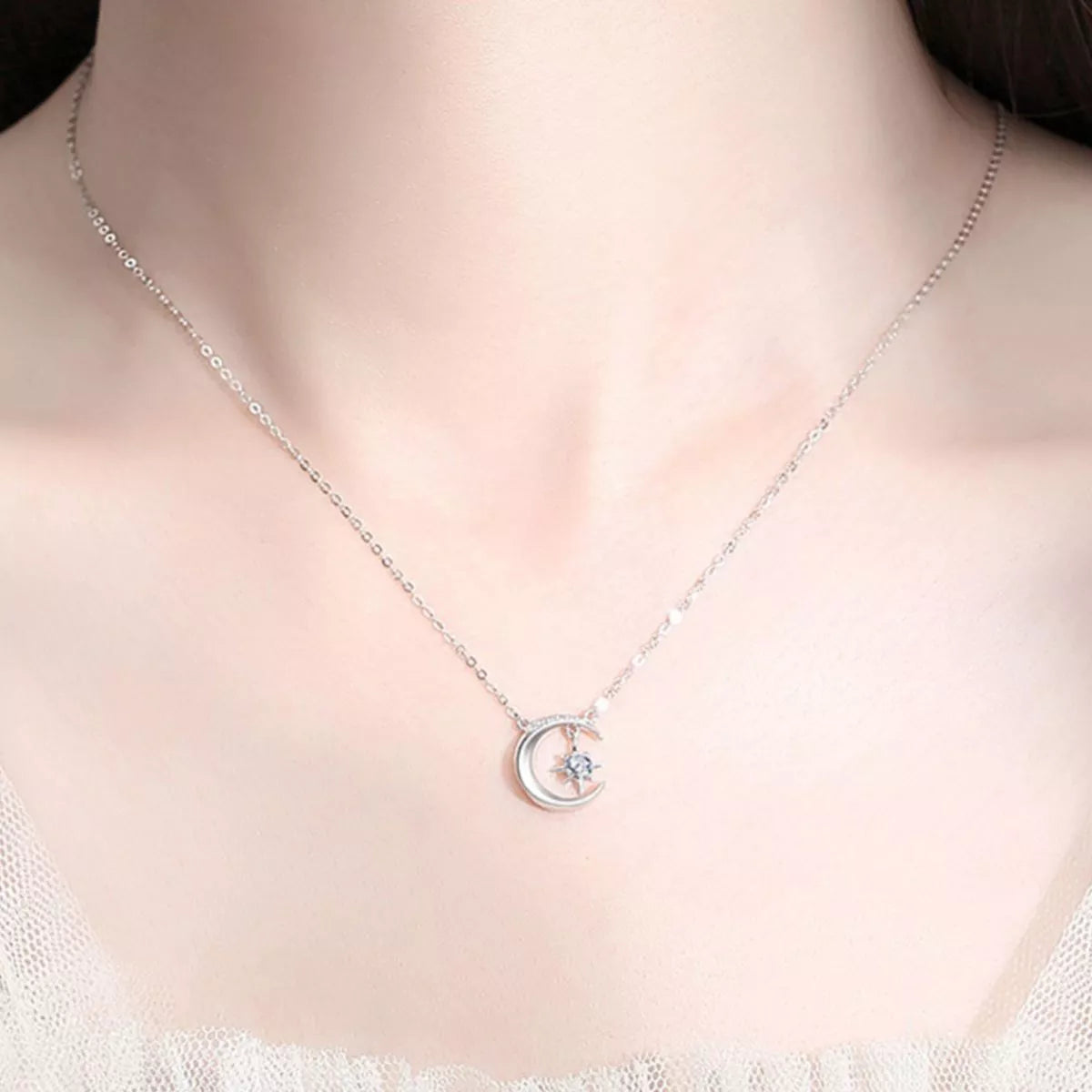 Silver necklace with a moon and star pendant on a person's neck