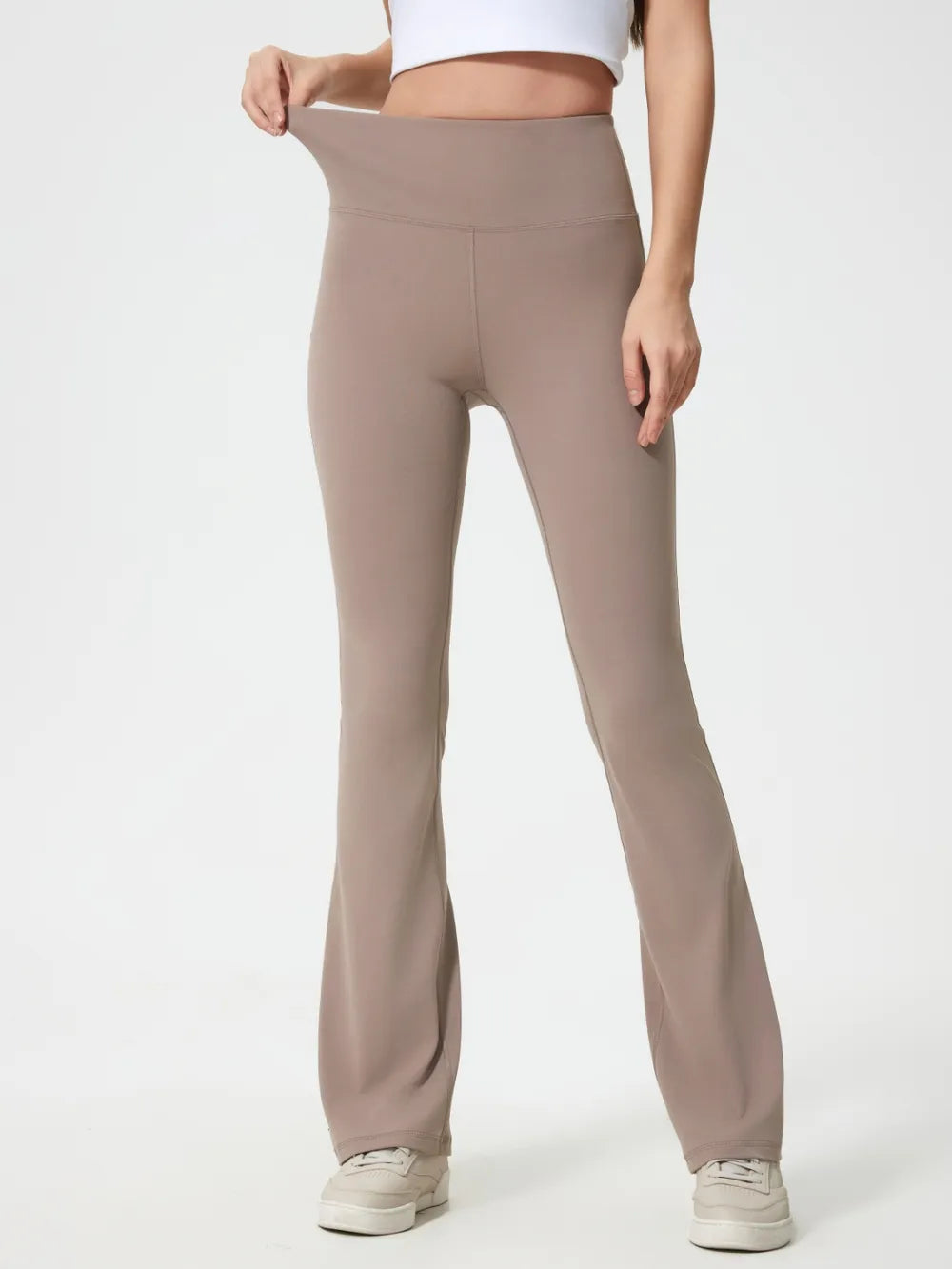 Beige flared pants worn by a person on a white background