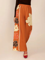 Orange pants with floral patterns on a beige background