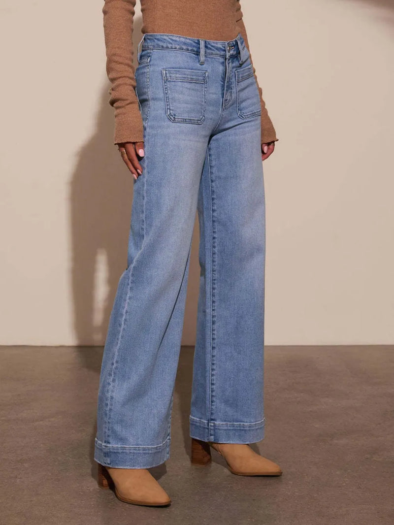 Person wearing blue jeans and a brown top against a plain background