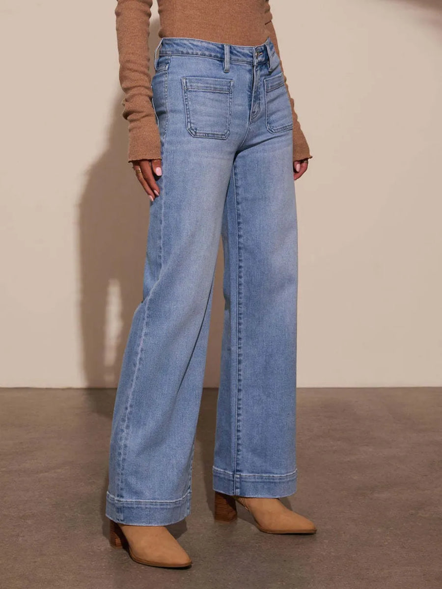 Person wearing blue jeans and a brown top against a plain background