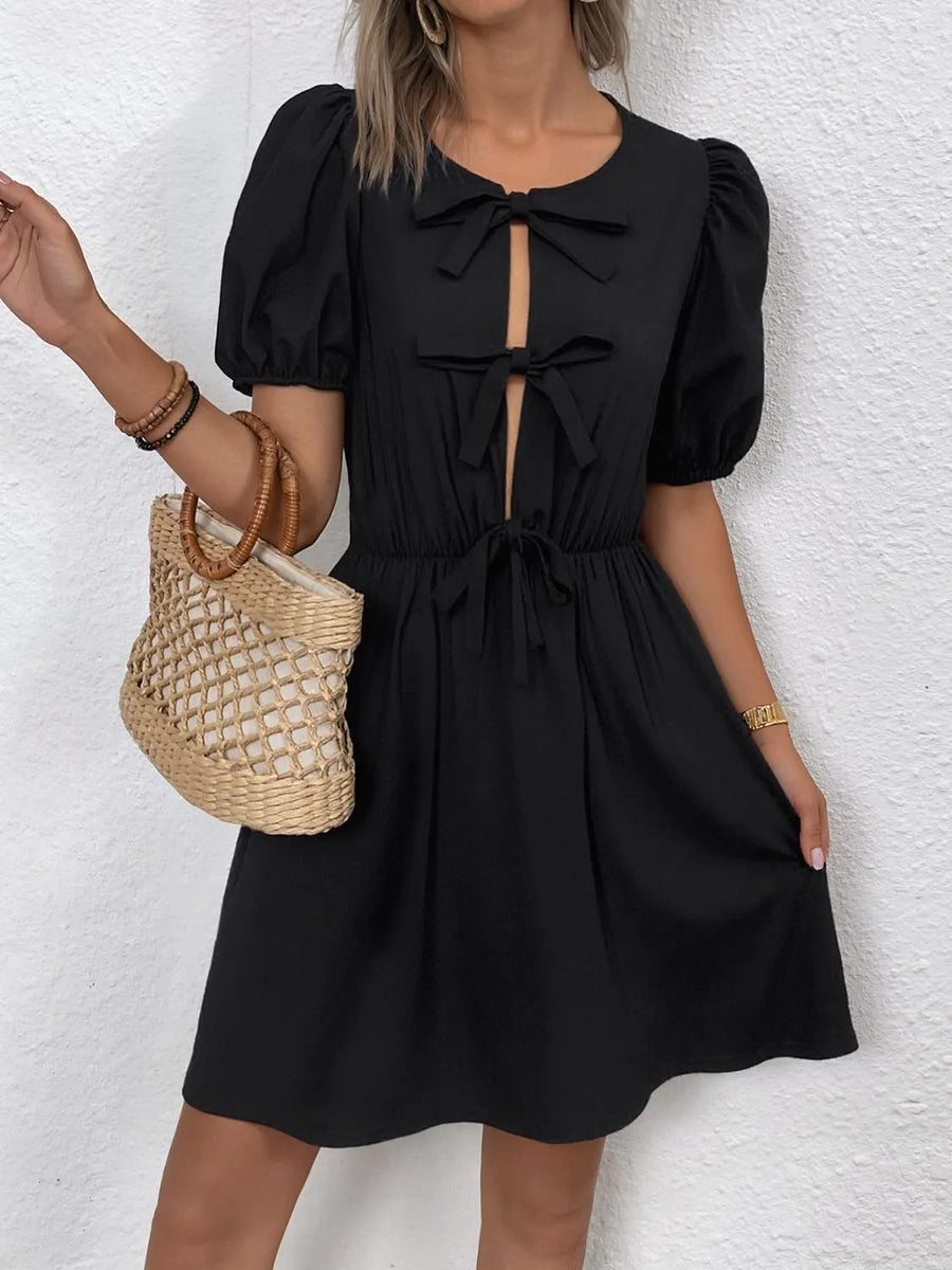 Woman wearing a black dress with puff sleeves against a white background