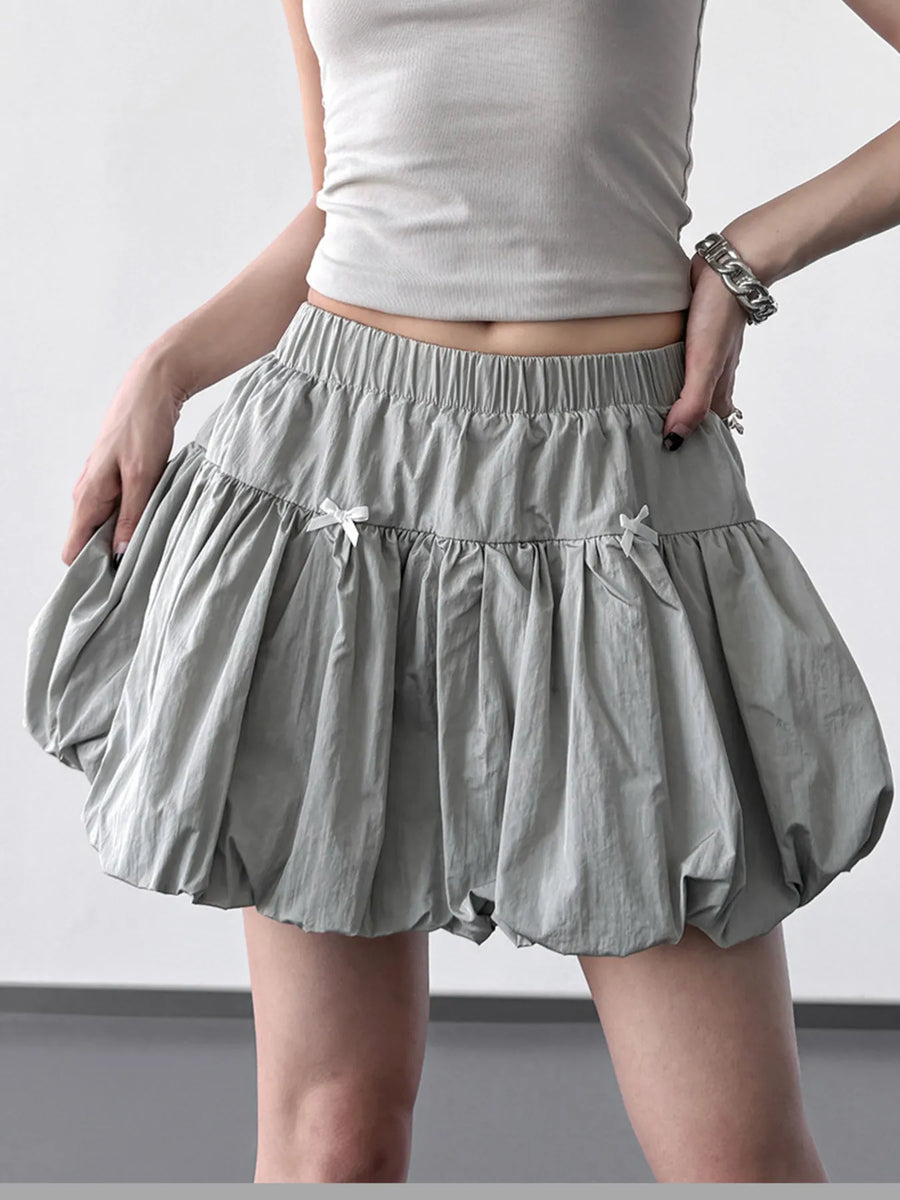 Person wearing a light gray skirt and tank top on a plain background