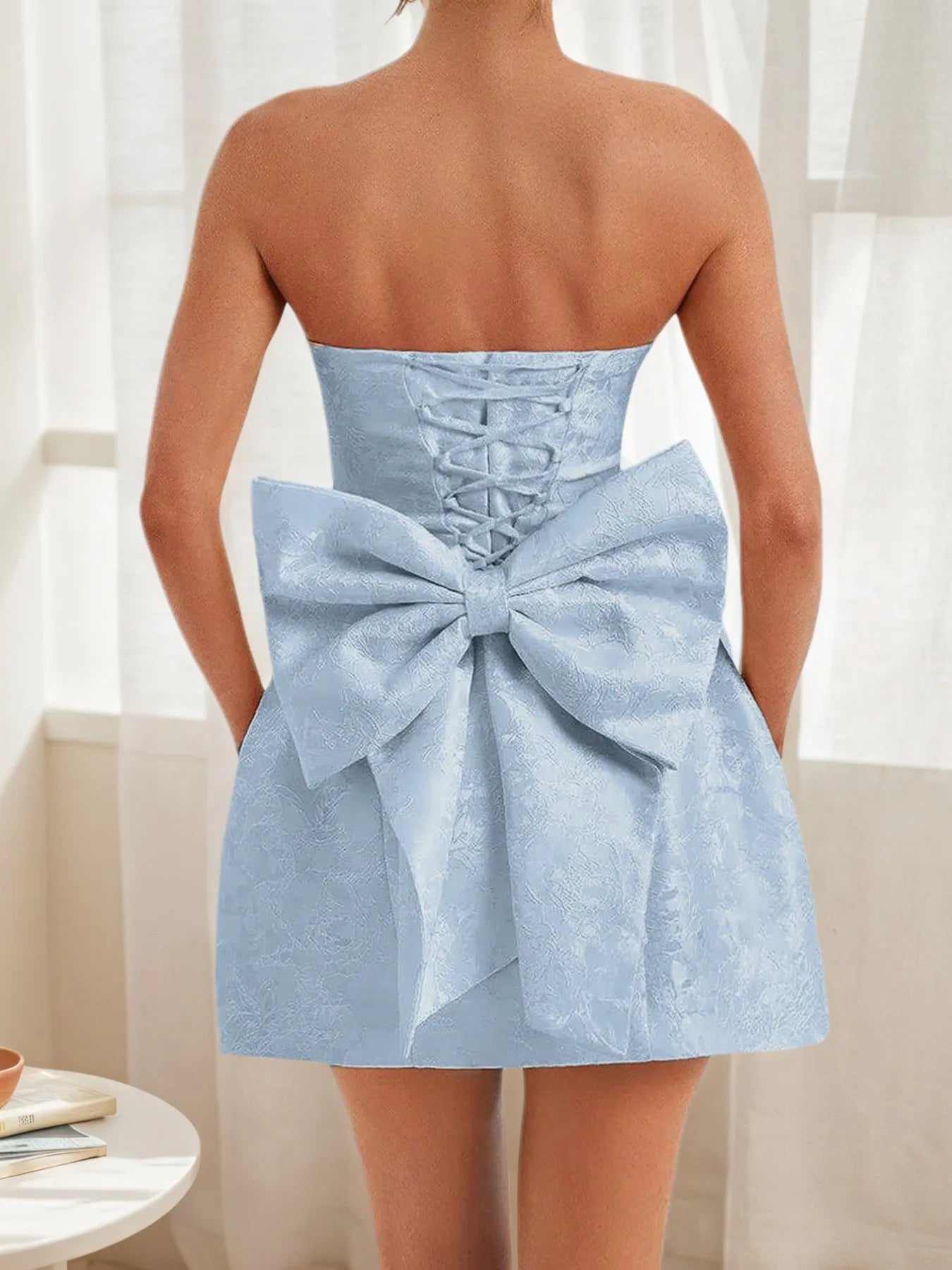 Light blue strapless dress with a large bow detail on a neutral background