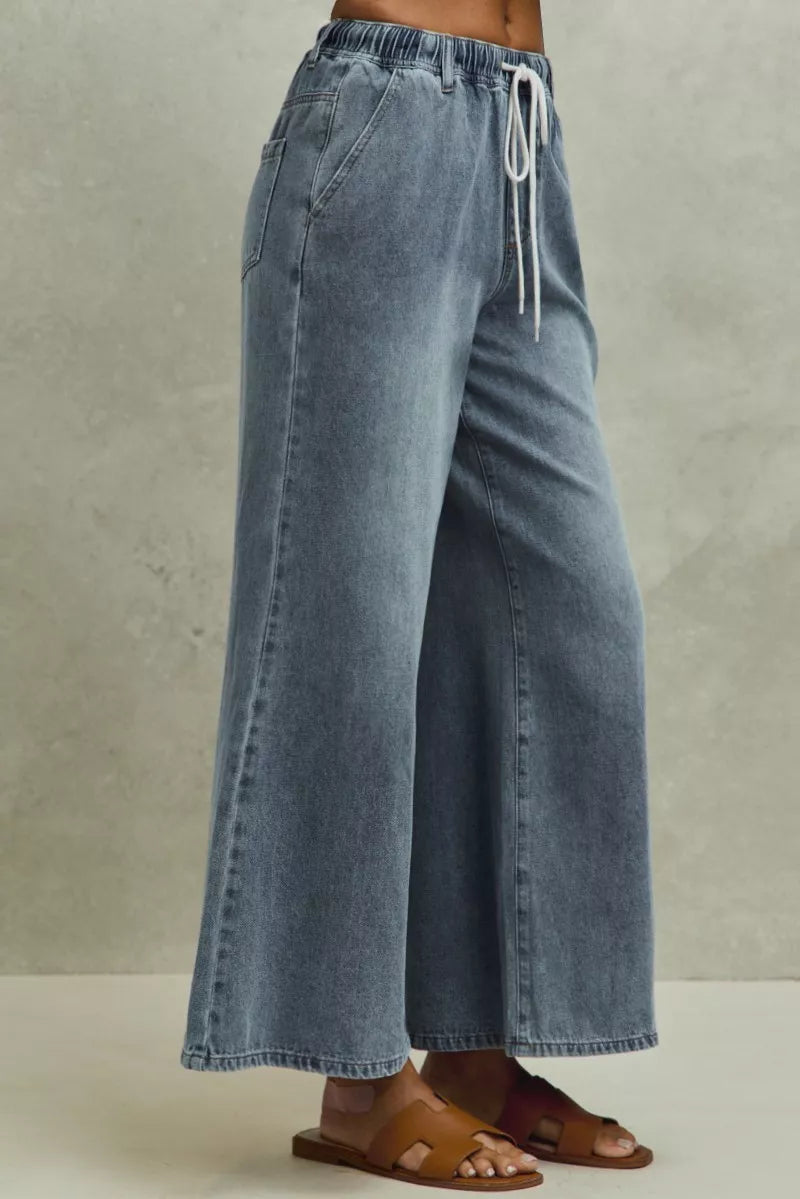 Blue denim wide-leg pants with a drawstring waist on a neutral background