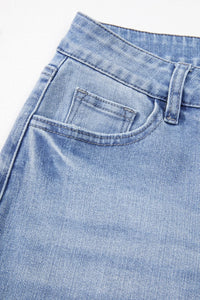 Close-up of blue denim jeans with a pocket detail on a light gray background