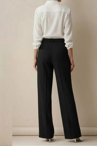Person wearing a white shirt and black pants against a beige background