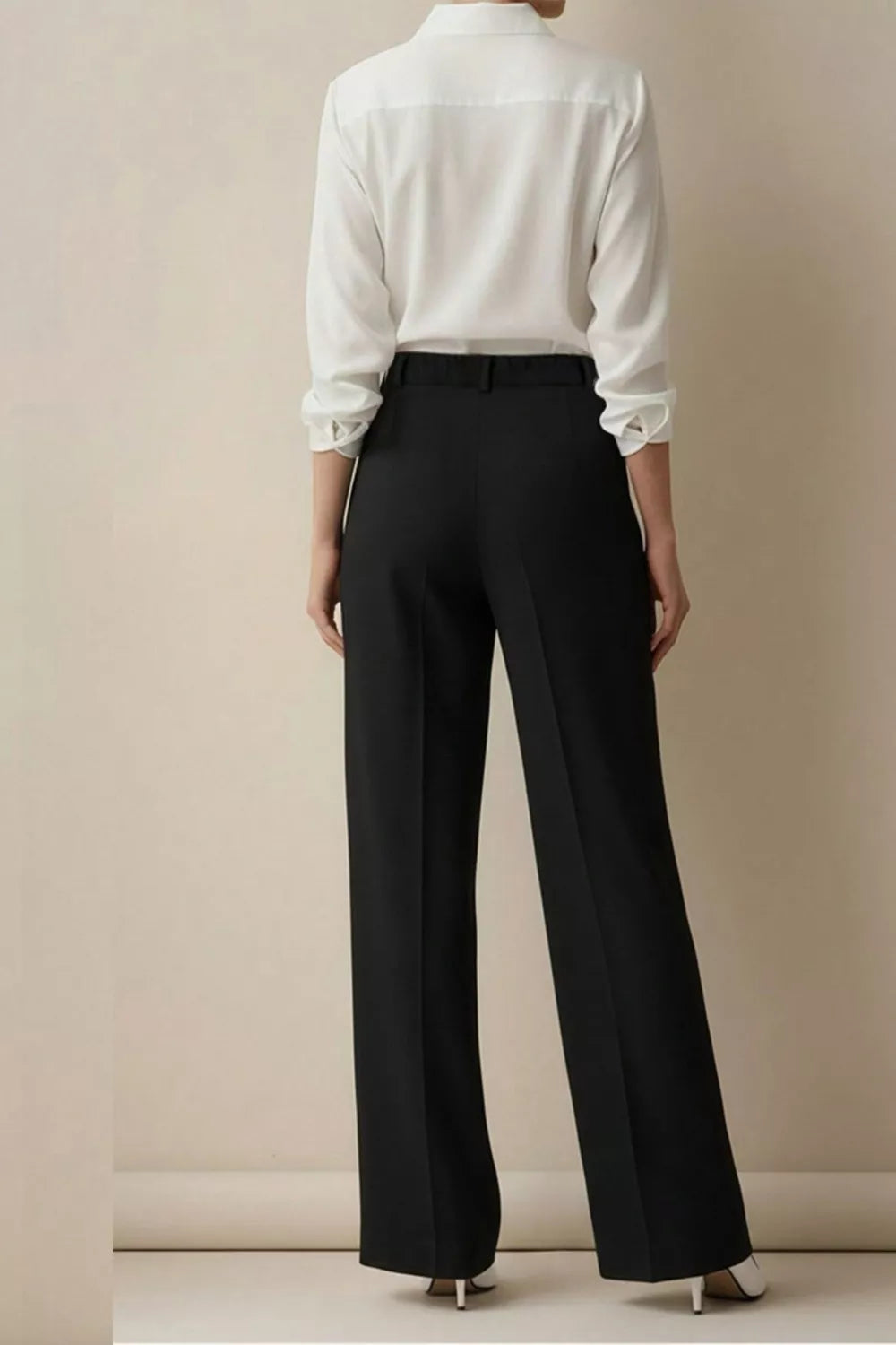 Person wearing a white shirt and black pants against a beige background