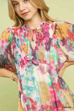 Woman wearing a colorful floral dress against a light green background