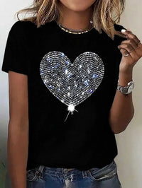 Black t-shirt with a sparkling heart design worn by a person.