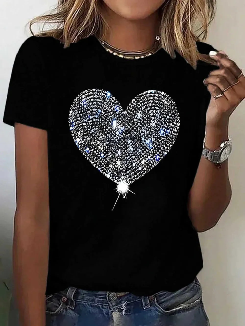 Black t-shirt with a sparkling heart design worn by a person.