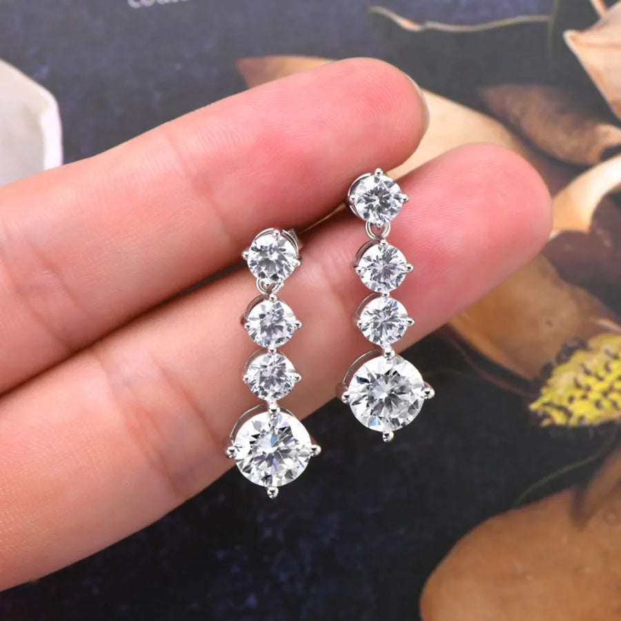Diamond earrings held between fingers against a blurred background