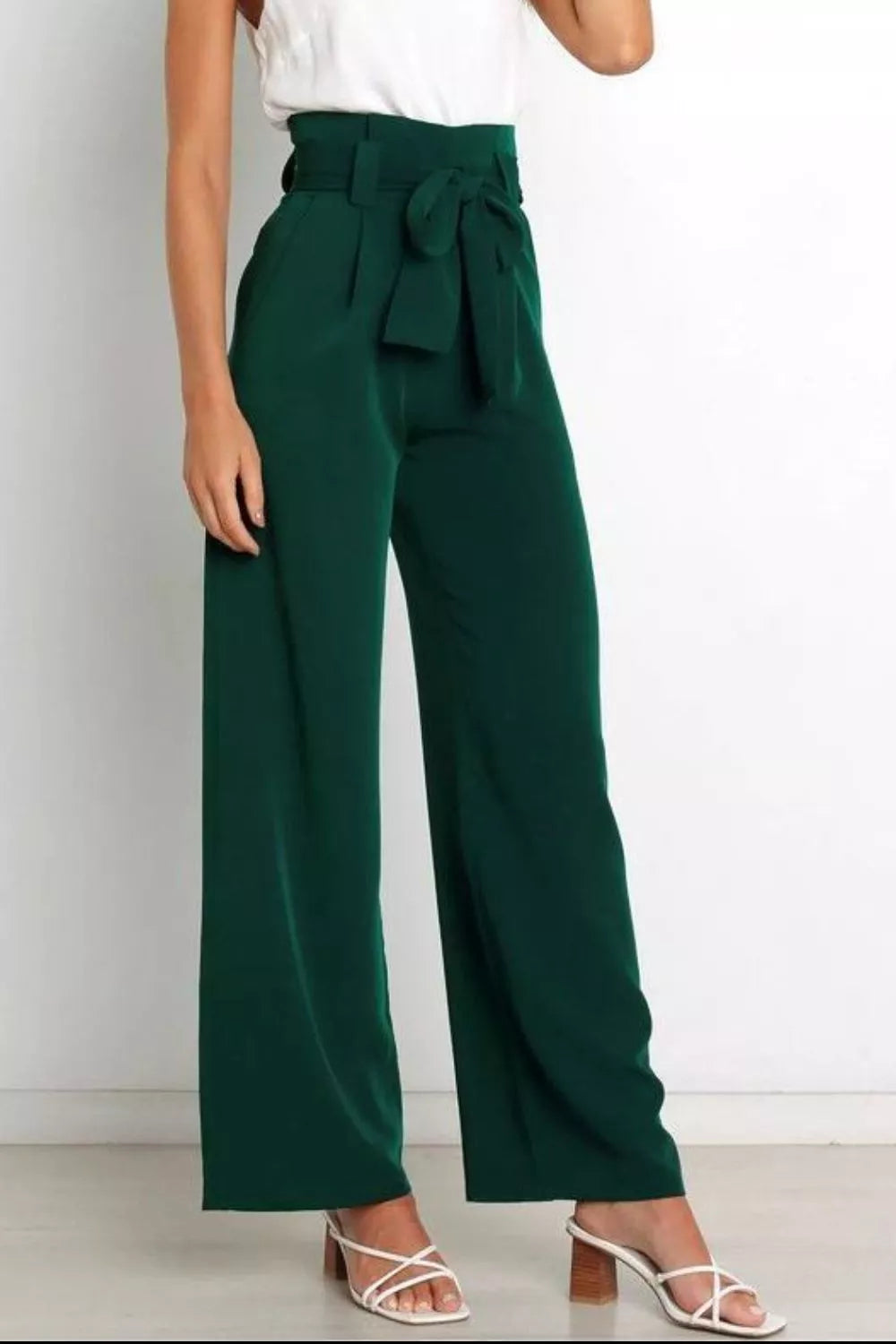Green wide-leg pants with a white top and sandals on a light background