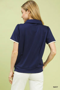 Woman wearing a navy polo shirt on a light green background