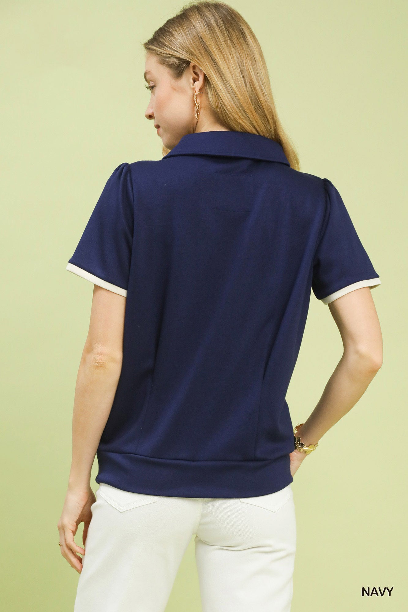 Woman wearing a navy polo shirt on a light green background