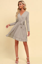 Woman wearing a gray wrap dress on a beige background