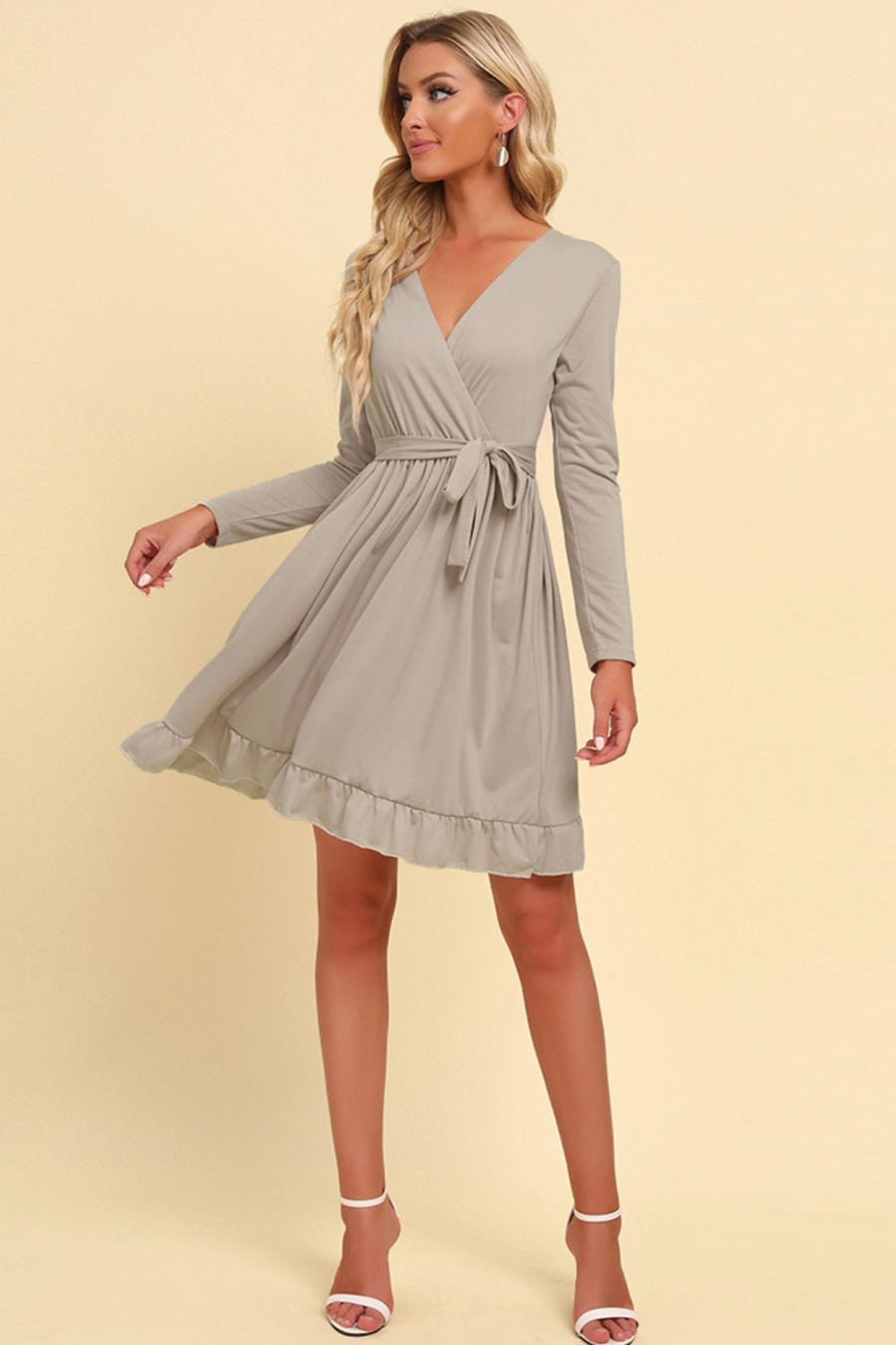 Woman wearing a gray wrap dress on a beige background