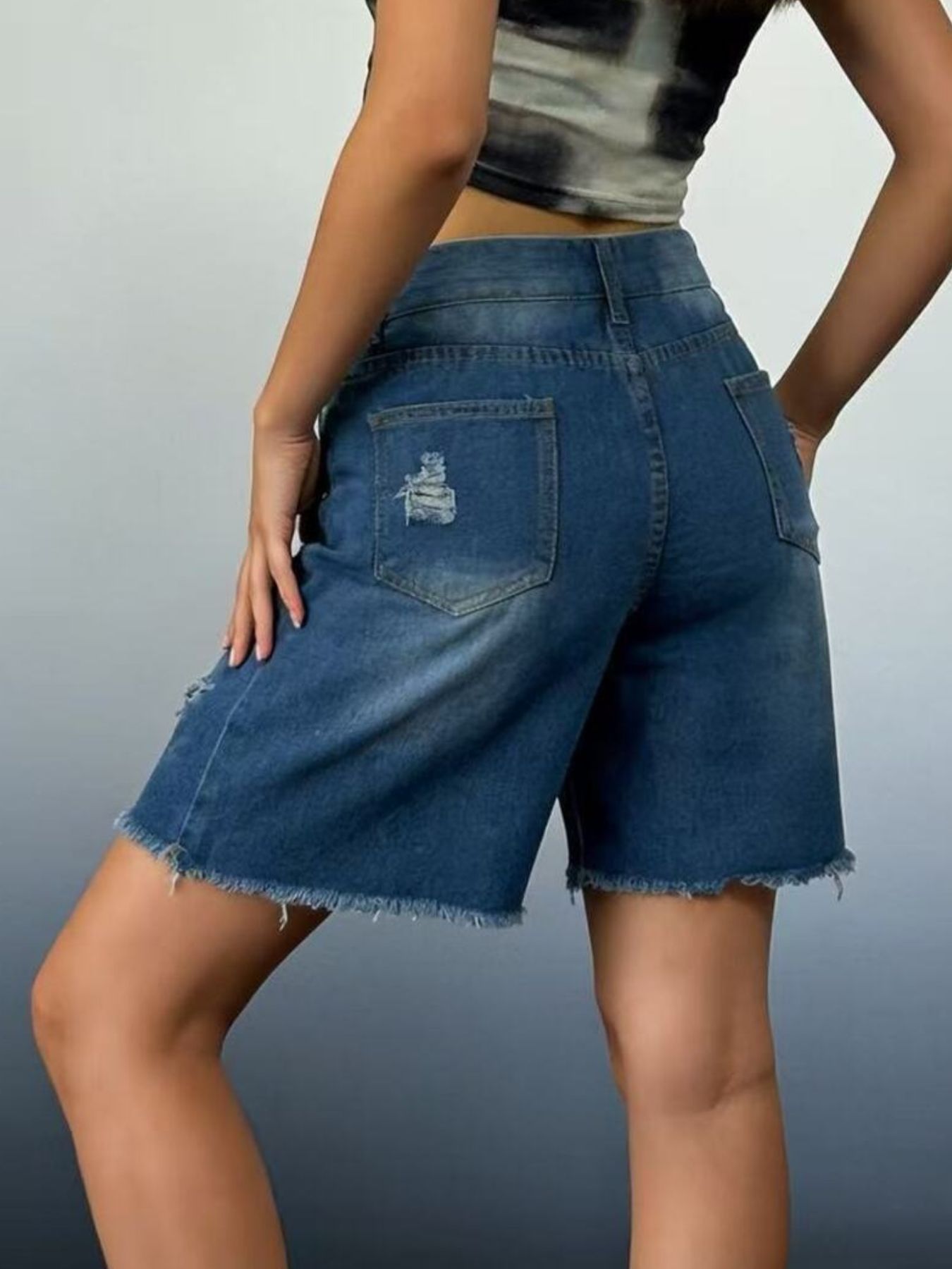 Person wearing blue denim shorts on a gray background