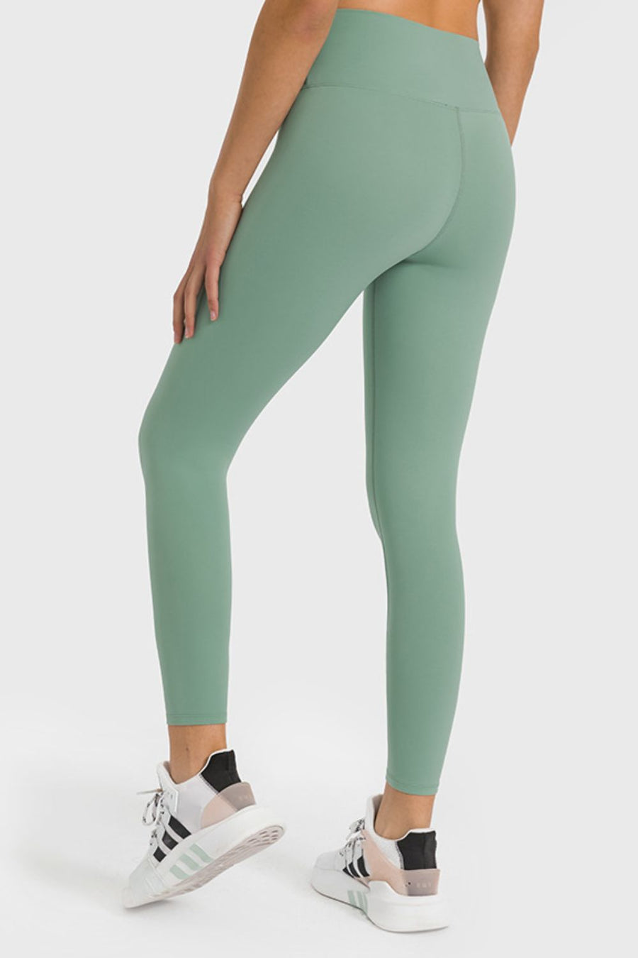 Person wearing green leggings and white sneakers on a white background