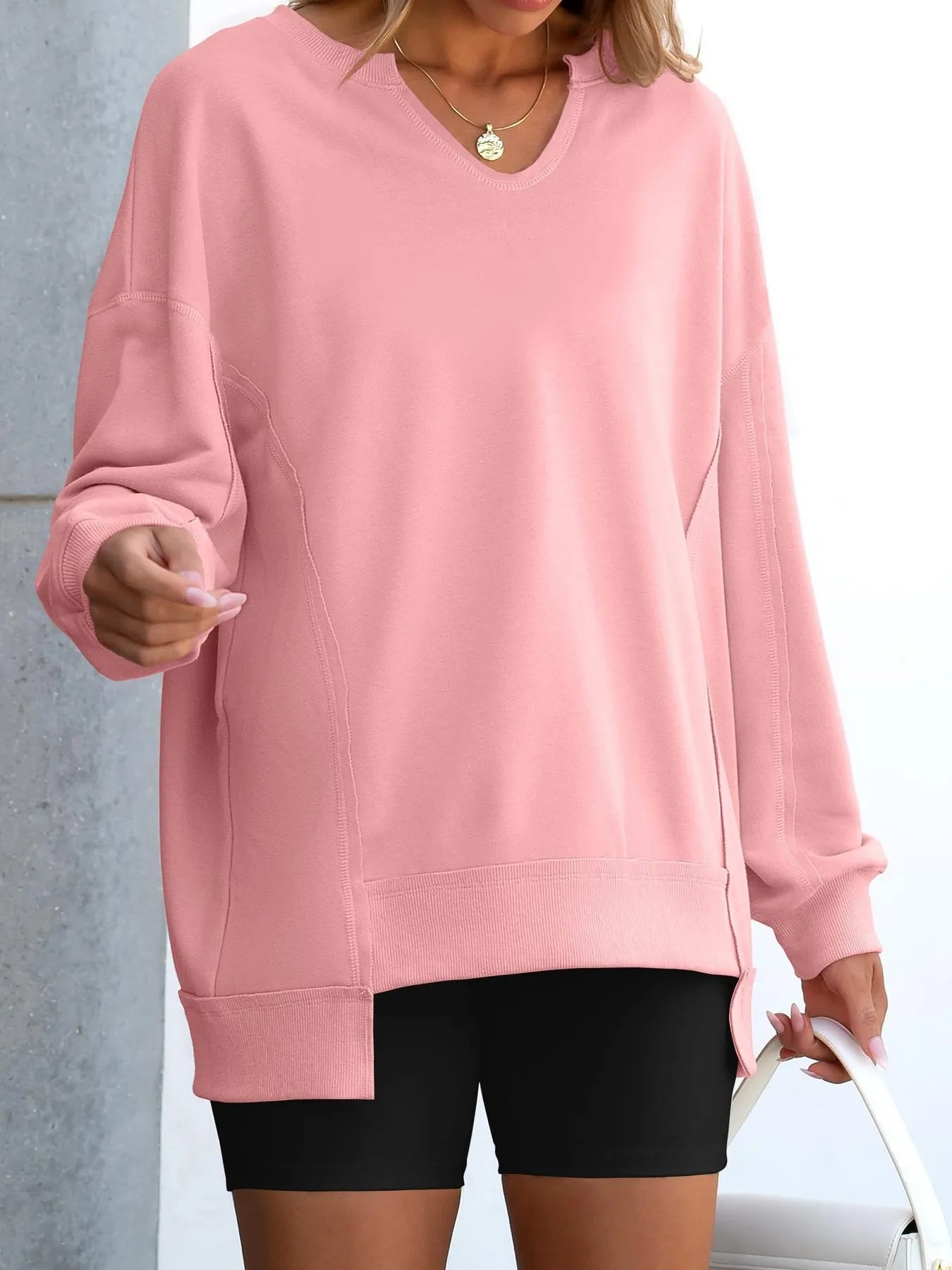 Person wearing a pink sweatshirt and black shorts against a neutral background