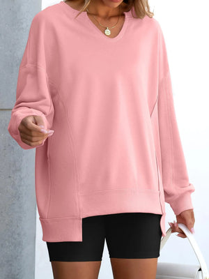 Person wearing a pink sweatshirt and black shorts against a neutral background