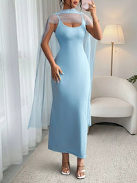 Woman wearing a light blue dress with sheer sleeves in a room.