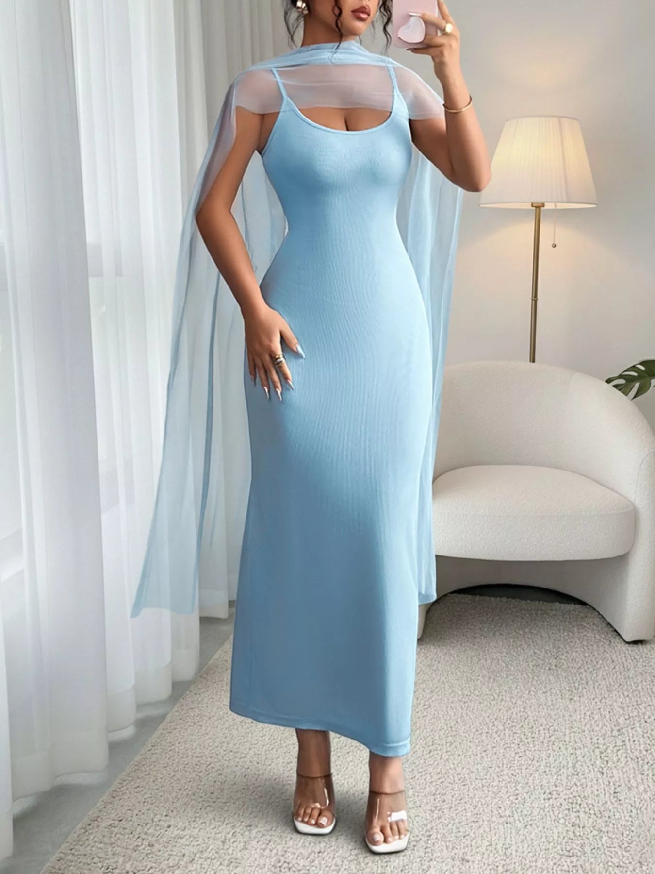 Woman wearing a light blue dress with sheer sleeves in a room.