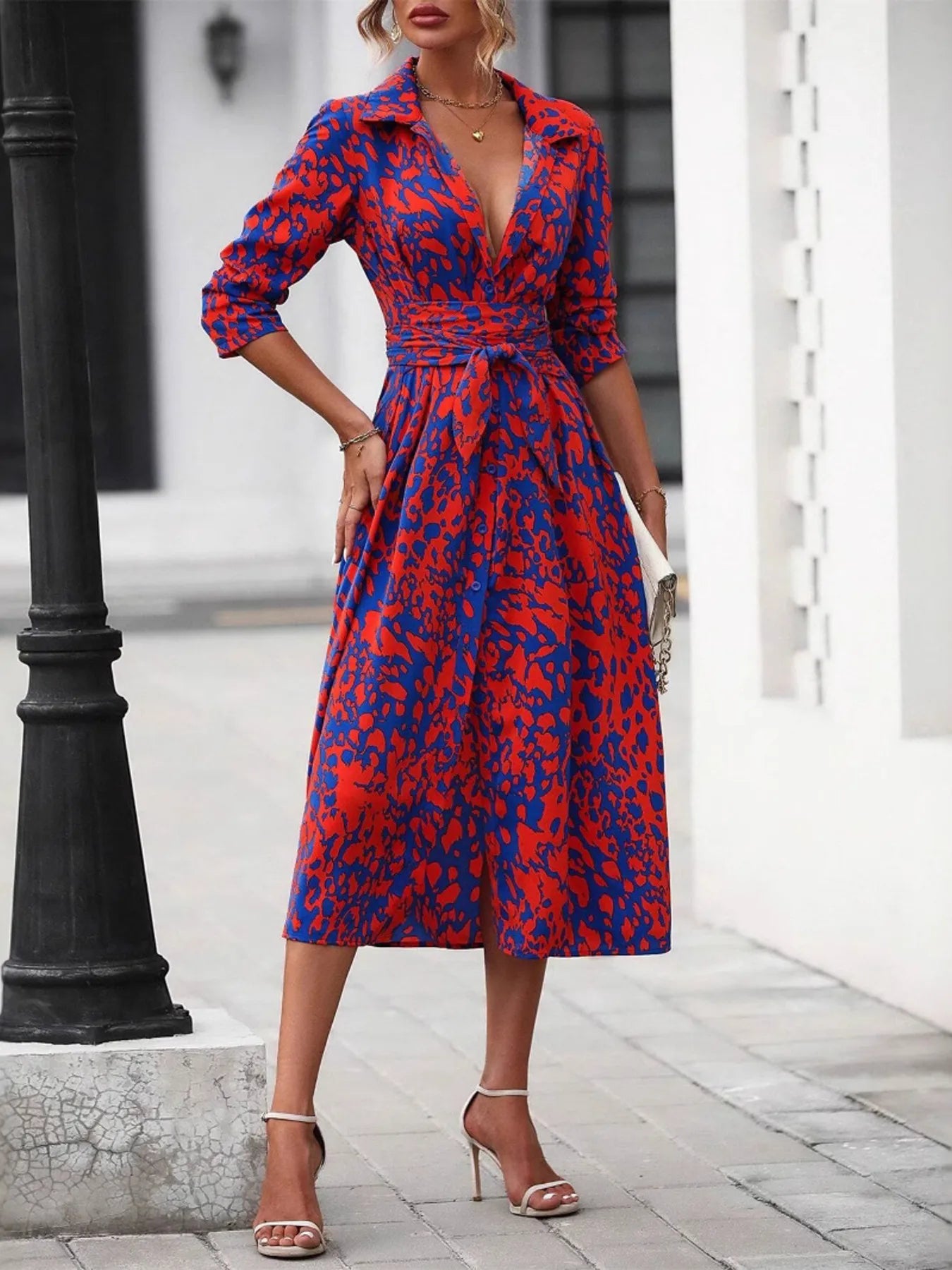 Woman wearing a red and blue patterned dress standing on a street.