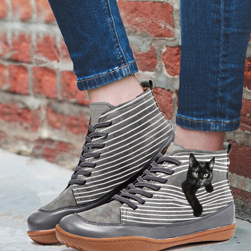 Gray high-top sneakers with striped pattern worn by a person against a brick wall.