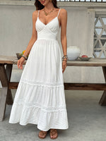 Woman wearing a white dress standing in front of a wooden table with decorative items.