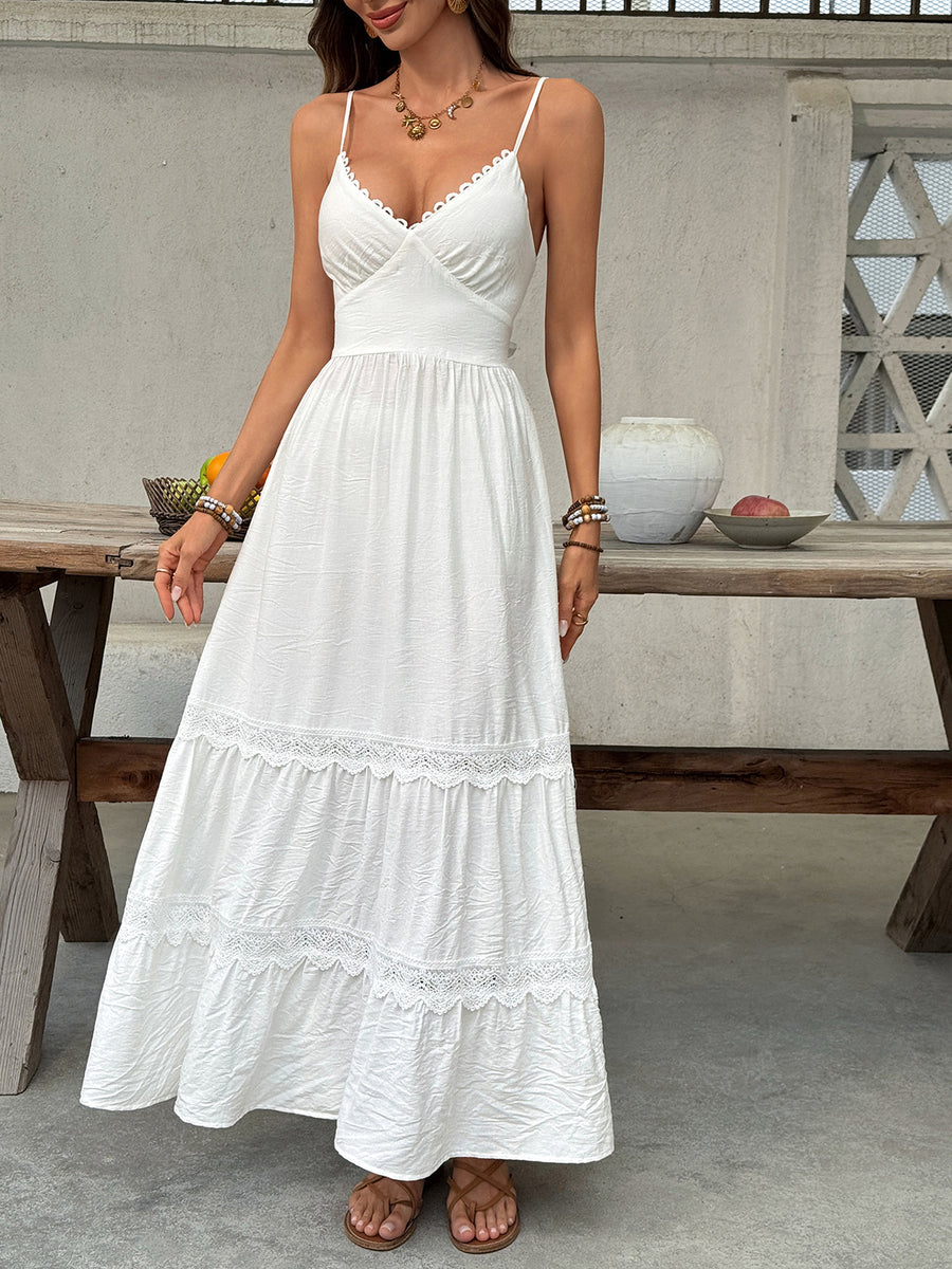 Woman wearing a white dress standing in front of a wooden table with decorative items.