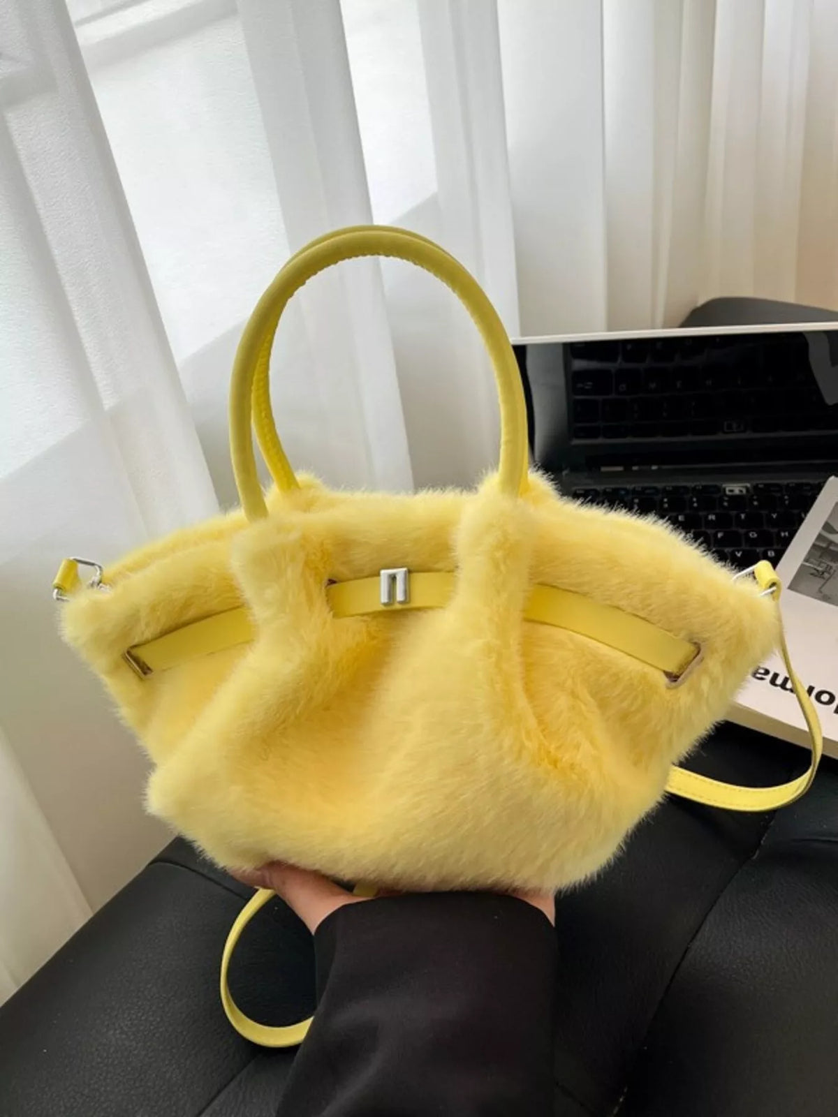 Yellow fluffy handbag held by a person with a blurred background