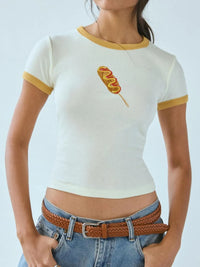 Person wearing a white crop top with a corn dog design and blue jeans.
