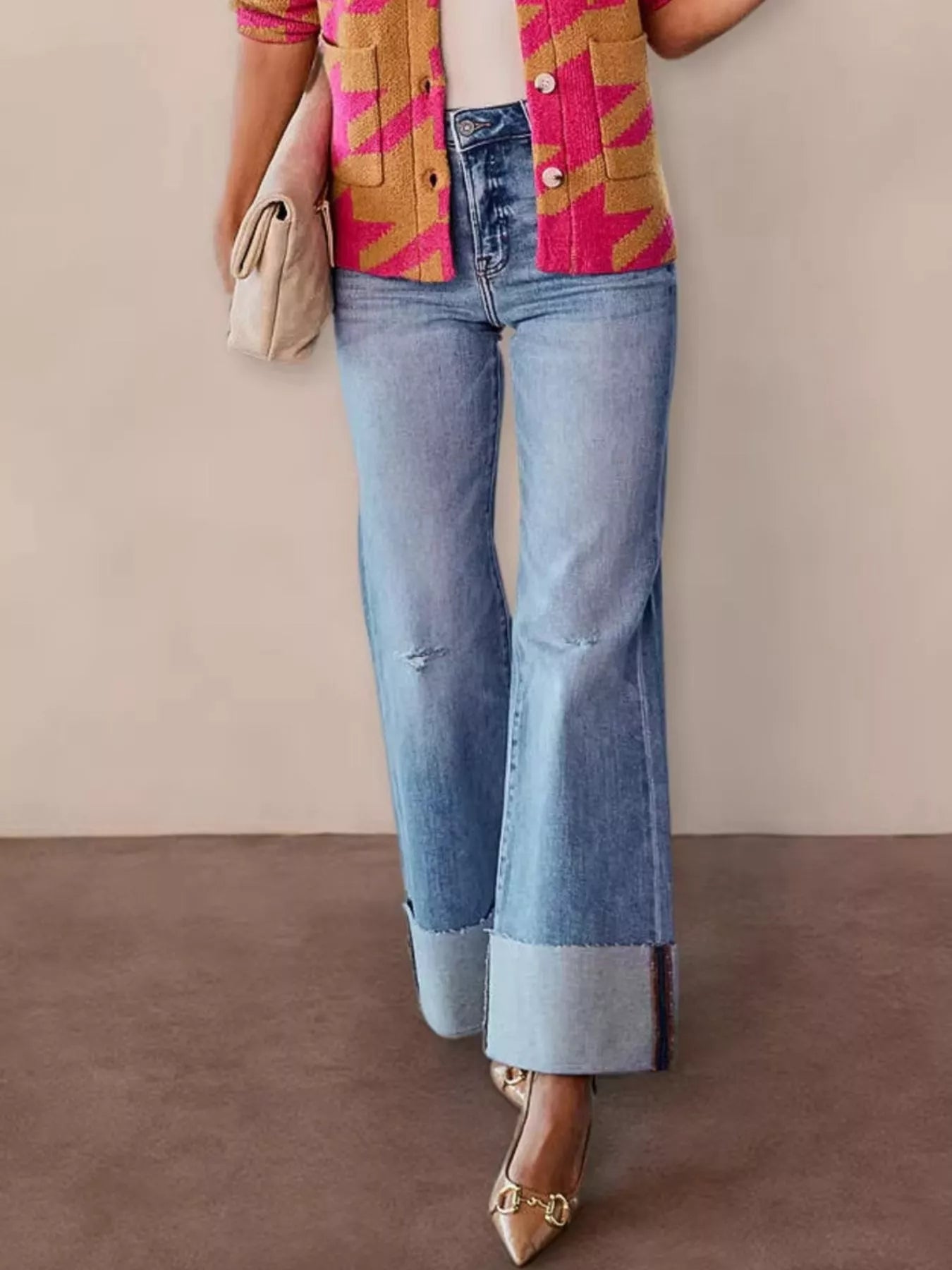 Person wearing a colorful jacket, blue jeans, and gold shoes on a plain background