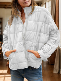 Person wearing a light gray quilted jacket indoors
