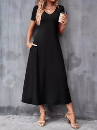 Woman wearing a black dress holding a coffee cup against a gray wall.