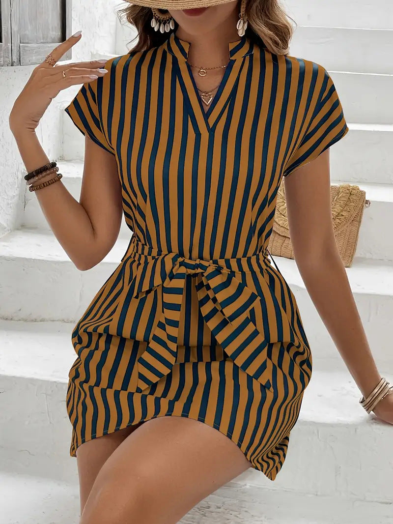 Woman wearing a striped dress sitting on white steps.
