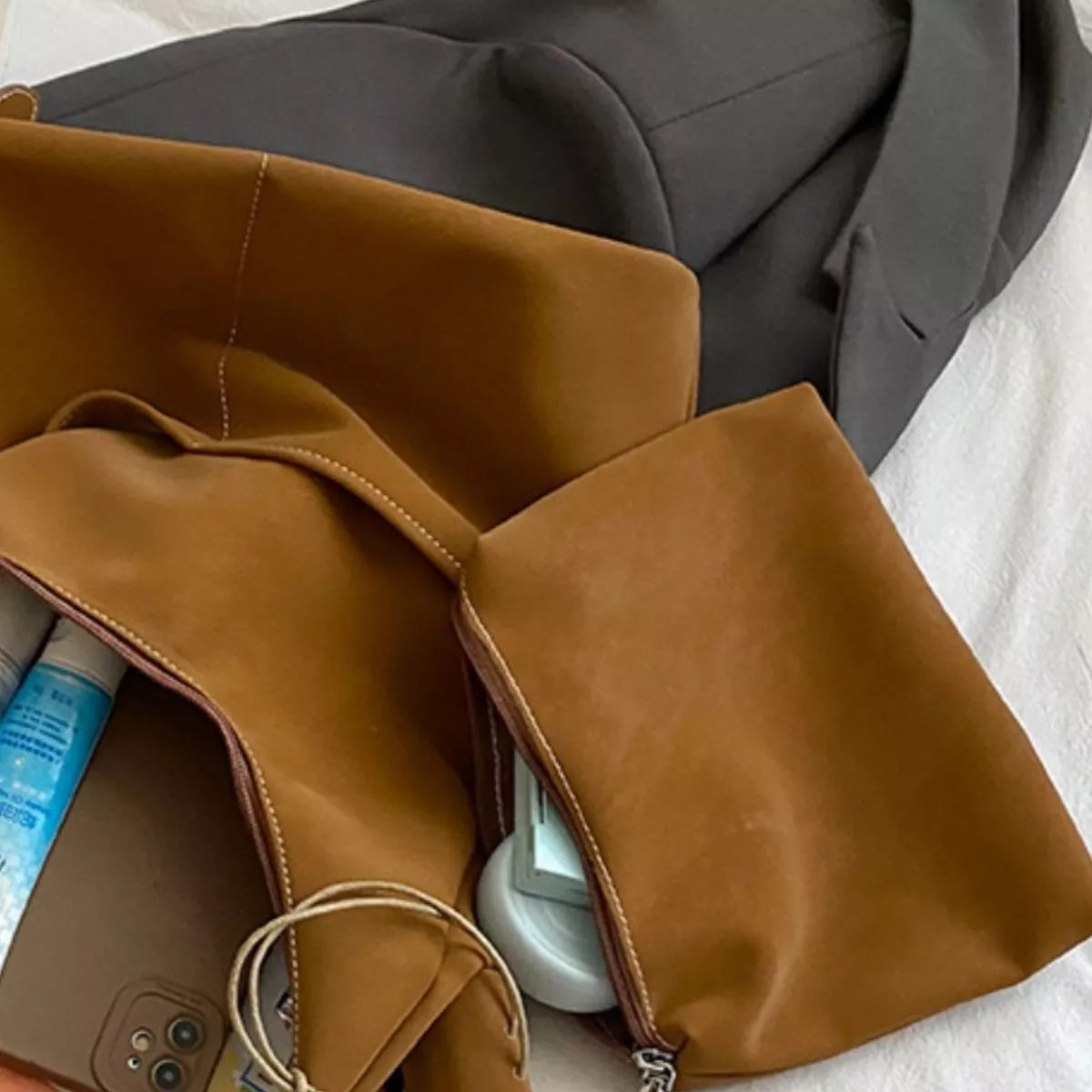 Brown leather bag with items inside on a white surface