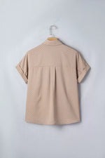 Beige polka dot shirt on a hanger against a light gray background