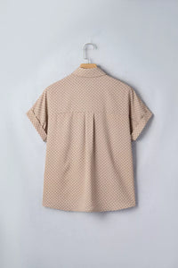 Beige polka dot shirt on a hanger against a light gray background