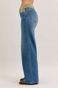 Blue jeans with a green patch on a white background