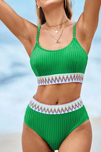 Green bikini with patterned waistband against a blurred beach background