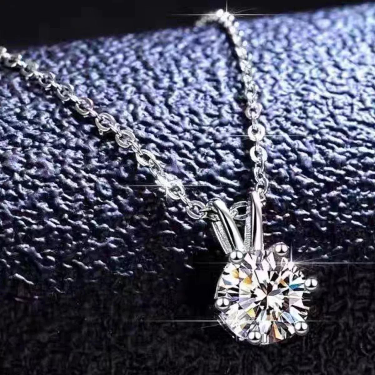 Silver necklace with a diamond pendant on a textured black background