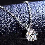 Silver necklace with a diamond pendant on a textured black background