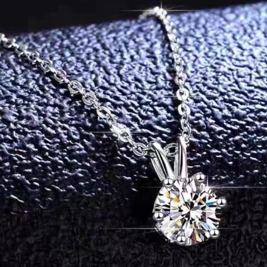 Silver necklace with a diamond pendant on a textured black background