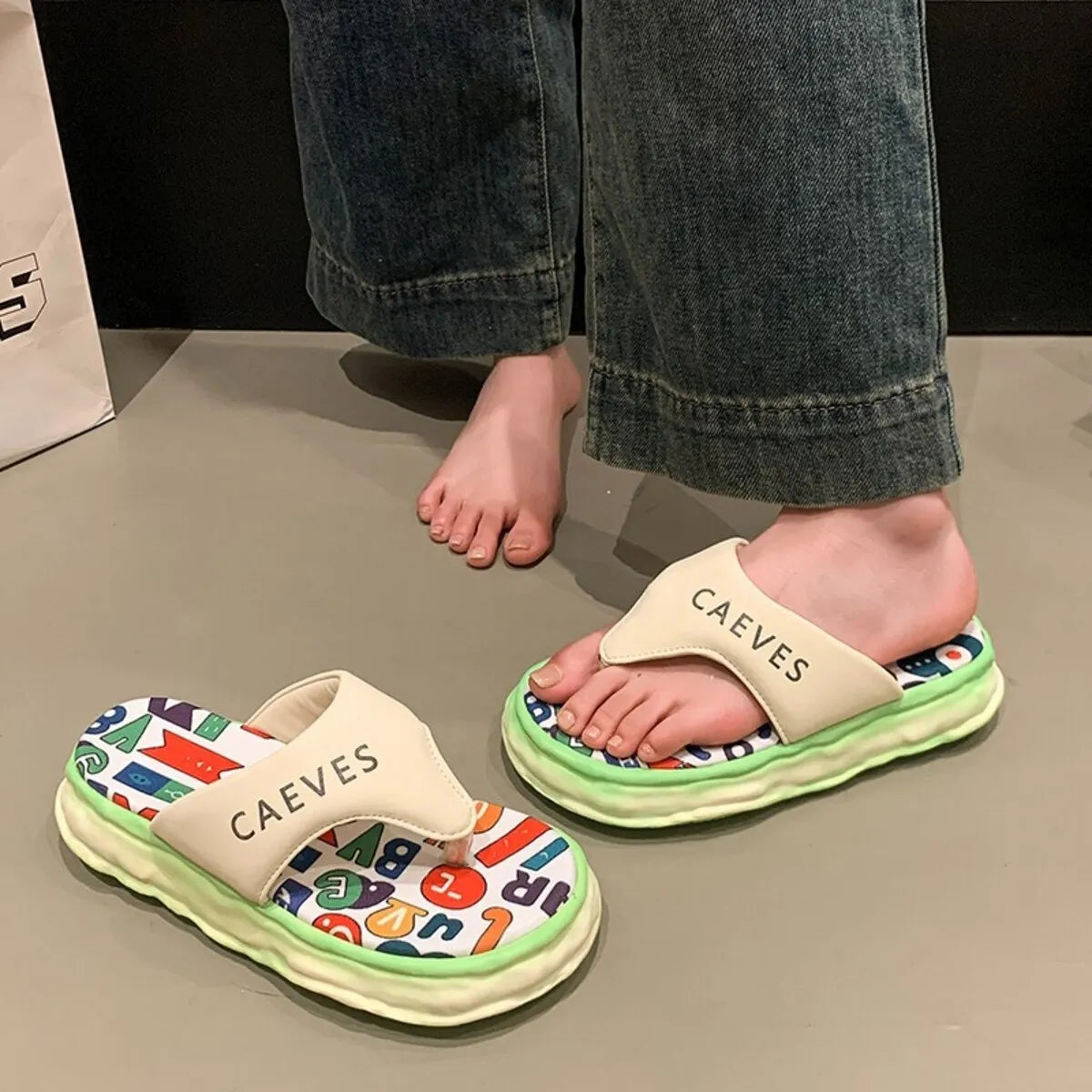Children's sandals with colorful sole and 'CAEVES' branding on a neutral background
