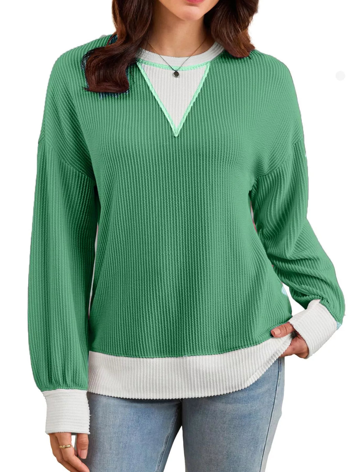 Green ribbed sweater with white trim worn by a person on a white background