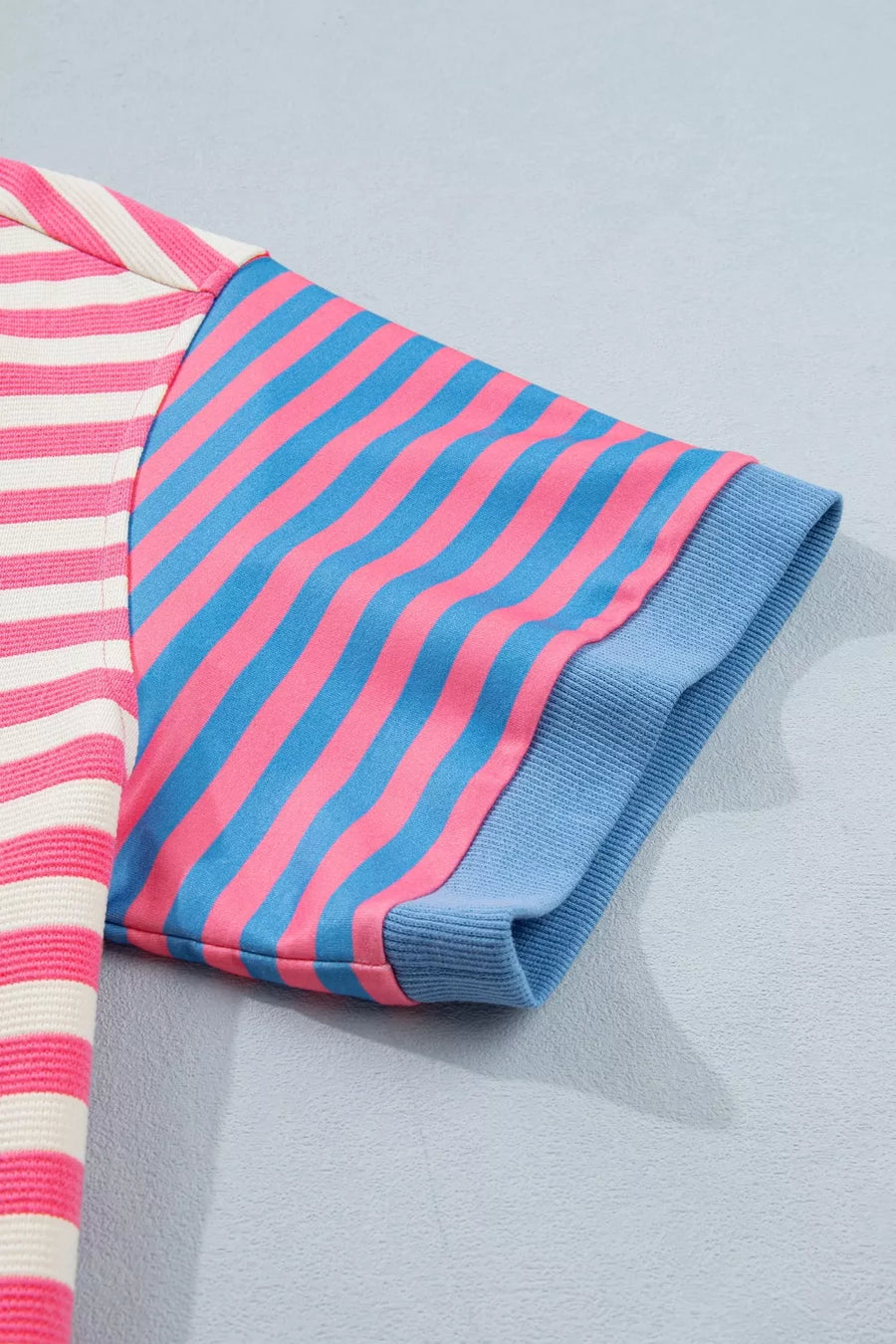 Striped fabric with pink and blue pattern on a light gray background