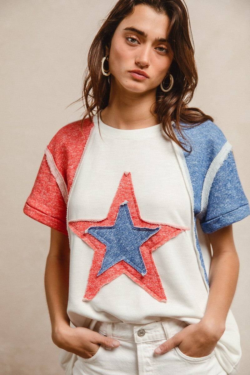 Woman wearing a colorful star-patterned top against a neutral background