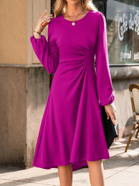 Woman wearing a purple dress standing outdoors with a blurred background
